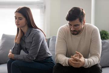 Couple sitting on couch thinking feels troubled about relations problems