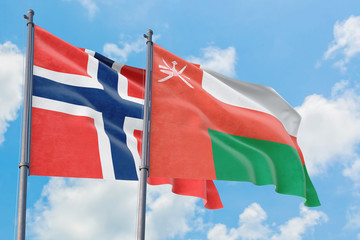 Oman and Bouvet Islands flags waving in the wind against white cloudy blue sky together. Diplomacy concept, international relations.