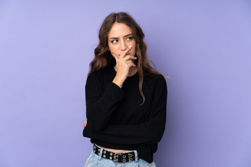 Young woman over isolated purple background having doubts and with confuse face expression