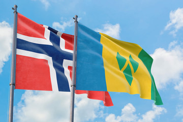 Saint Vincent And The Grenadines and Bouvet Islands flags waving in the wind against white cloudy blue sky together. Diplomacy concept, international relations.