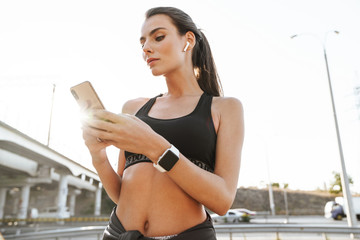 Fitness woman outdoors using mobile phone.