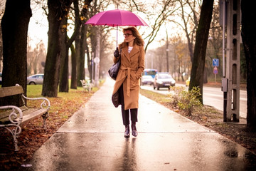 Confident woman walking on the street on a rainy day