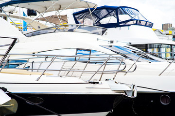 Nautical background of a row of luxury yachts, with black tinted windows and chrome metal railings...