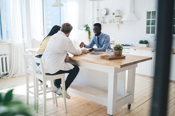 Cheerful agent talking with couple in bright kitchen