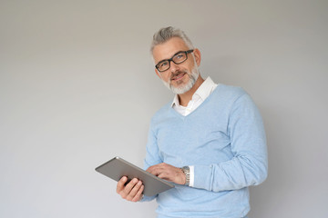Middle-aged man using tablet, isolated on grey background