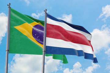 Costa Rica and Brazil flags waving in the wind against white cloudy blue sky together. Diplomacy concept, international relations.