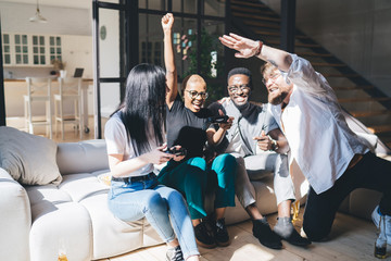 Diverse cheerful company of friends celebrating victory after playing video games © BullRun
