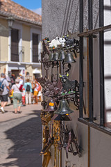 Various metal doorbells with figures of bull, horse, birds and flowersare placed for sale on the wall of a tourist street. Soft focus