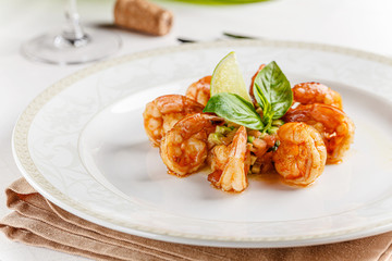 Spanish, Italian cuisine. King prawns with sauce. Serving dishes in a restaurant on a white plate, next to a glass of white wine. background image, copy space text