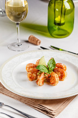 Spanish, Italian cuisine. King prawns with sauce. Serving dishes in a restaurant on a white plate, next to a glass of white wine. background image, copy space text