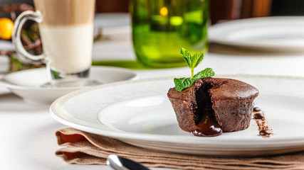French cuisine Chocolate fondant dessert on a white plate. Baked cupcake with liquid chocolate inside. background image, copy space text