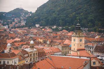 Fototapeta premium Brasov, Romania - 10/04/2017: orange roofs and clock tower in old city.