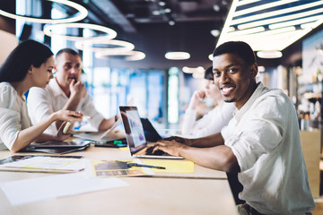 Cheerful African American manager with laptop during meeting