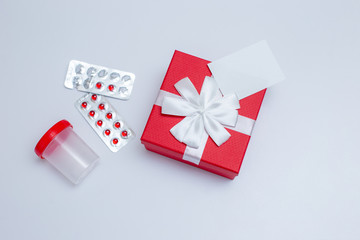 A red box with a gift and a white card for text, blisters with red capsules