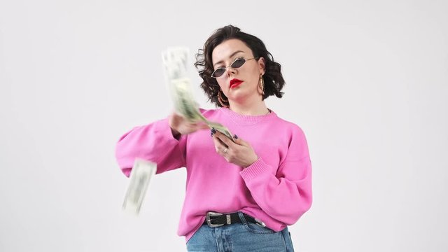 Rich chic woman, stylish fashion blogger, throwing money, scatter the dollars, spending money on useless thing.  