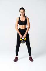 Fitness woman exercising crossfit holding kettle bell. Fitness instructor on white background