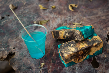 Casting blue epoxy resin burl wood cube on old table art background