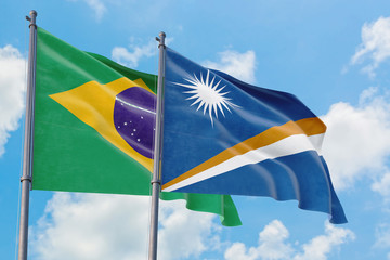 Marshall Islands and Brazil flags waving in the wind against white cloudy blue sky together. Diplomacy concept, international relations.