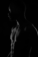 Fototapeta na wymiar black and white portrait of a handsome black man with naked sports torso on dark background
