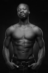 Fototapeta na wymiar black and white portrait of a handsome black man with naked sports torso looking in the camera on dark background