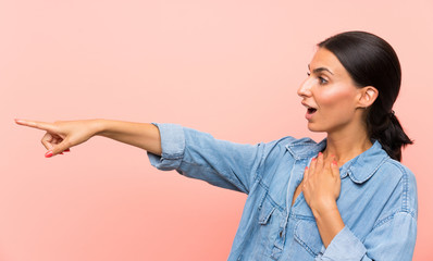 Young woman over isolated pink background pointing finger to the side