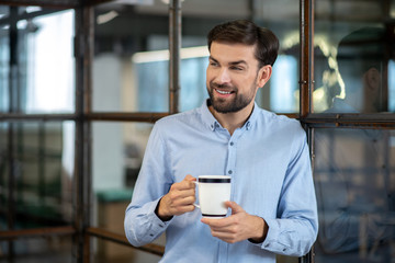 Young bearded man in a blue shirt smiling and feeling relaxed