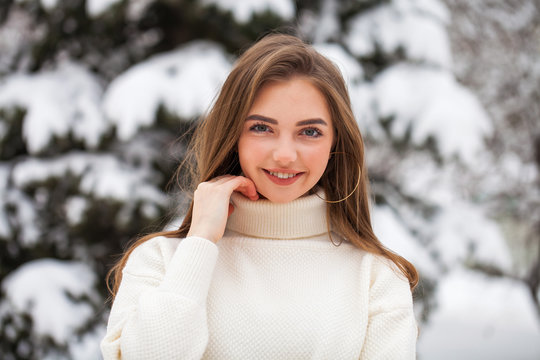 Young beautiful woman in a woolen sweater posing on a background of a winter park
