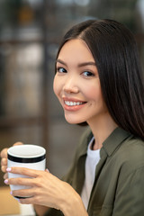 Long-haired brunette asian girl sitting and having coffee