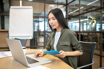 Long-haired brunette asian girl working on a laptop