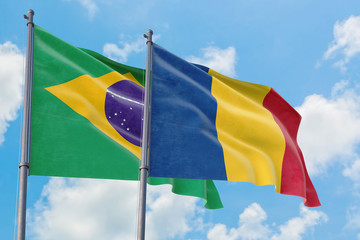 Romania and Brazil flags waving in the wind against white cloudy blue sky together. Diplomacy concept, international relations.
