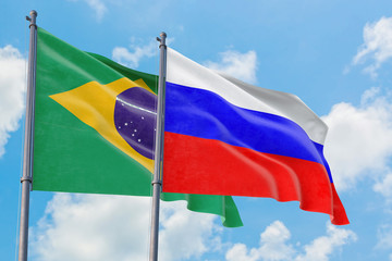 Russia and Brazil flags waving in the wind against white cloudy blue sky together. Diplomacy concept, international relations.