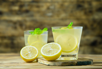 Lemonade or mojito cocktail with lemon and mint on wood background