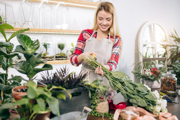 woman florist composing and creating wonderful bouquet of flowers, enjoy working in her own shop or garden. floral business concept