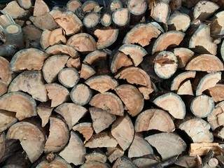 Firewood and logs are in one heap. Chopped wood as a solid fuel. Round oak beams.