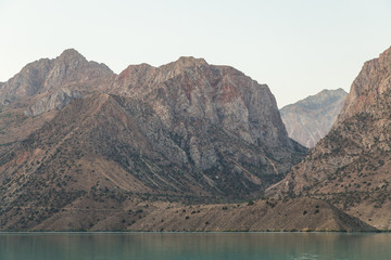 Mirror surface of Lake Iskanderkul at dawn amid the mountains