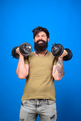 Fototapeta na wymiar Bearded man raising dumbbells. Sportsman making weightlifting. Man with dumbbells during an exercise. Muscular fitness man working out with dumbbells. Strong handsome sportsman making weightlifting.
