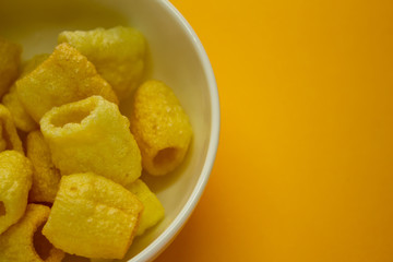 Far-far (also fryum) in a bowl which is an Indian snack food composed primarily of potato starch and tinted sago.