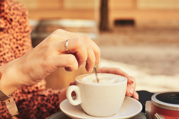 Trendy woman drinking coffee outdoors.