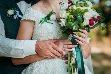 Groom and bride holding colorfull wedding bouquet in the hand
