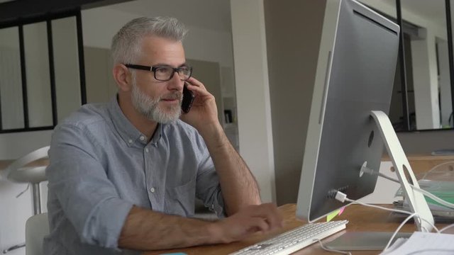 Architect working in office on desktop, talking on phone