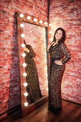 Fat plump charming cute woman with black curly hair in black beautiful dress in the room with...