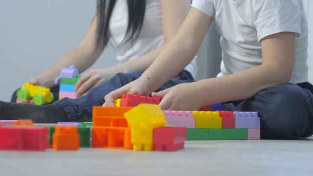 childhood happy family mom and children are playing concept little girl and boy brother and sister lifestyle collects constructor teamwork. child plays toys sitting floor. children play in team toys