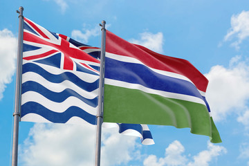 Gambia and British Indian Ocean Territory flags waving in the wind against white cloudy blue sky together. Diplomacy concept, international relations.