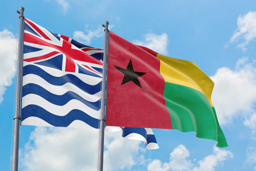 Guinea Bissau and British Indian Ocean Territory flags waving in the wind against white cloudy blue sky together. Diplomacy concept, international relations.