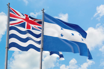 Honduras and British Indian Ocean Territory flags waving in the wind against white cloudy blue sky together. Diplomacy concept, international relations.