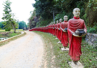 Statues of monks in robes collecting alms near the Myanmar monastery