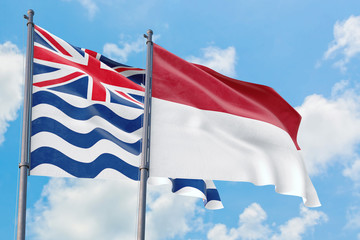 Indonesia and British Indian Ocean Territory flags waving in the wind against white cloudy blue sky together. Diplomacy concept, international relations.