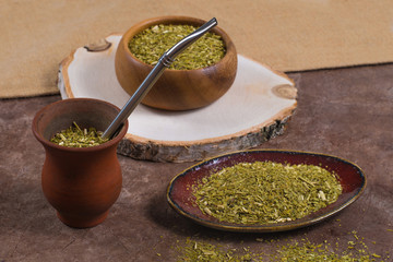 South American yerba mate tea dried leaves in bowls with porongo on stone background