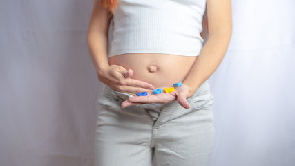 Pregnant woman is trying on her jeans or clothing that does not fit on her growing belly anymore in the first trimester