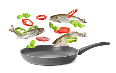 Many different ingredients falling into frying pan on white background. Delicious recipe